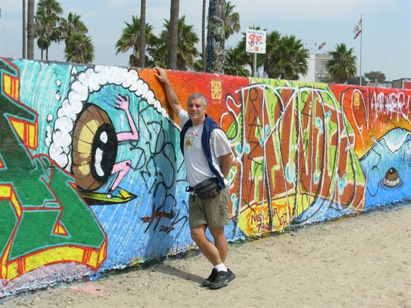 Man leaning on colorful graffiti wall at Venice Beach