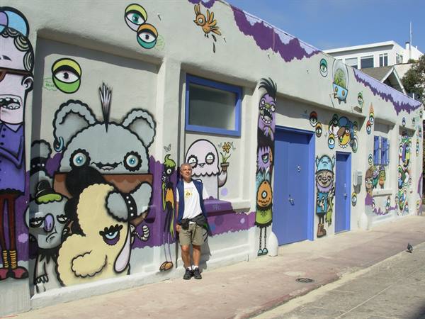 Man in front of a wall painted with colorful cartoon characters and blue doors