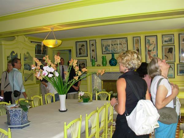 Visitors in yellow dining room with long table and orchid centerpiece