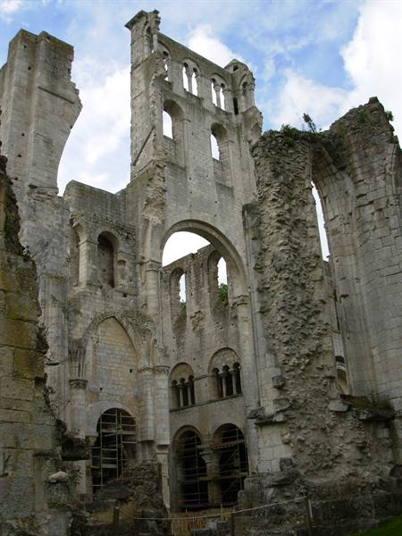 Stone ruins of a Gothic abbey, tall arches under a cloudy sky