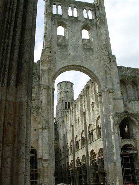Stone arch and tower of Jumièges Abbey among ruins and scaffolding