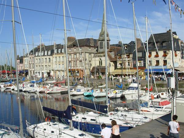 Sailboats moored in Honfleur harbor in front of old timbered buildings
