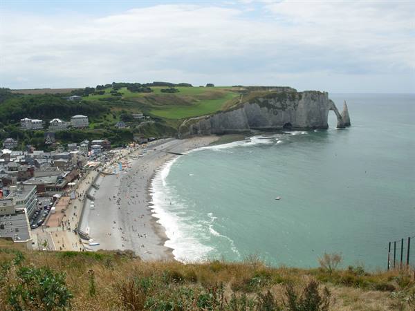 Étretat beach with white chalk cliffs and natural arch above the sea