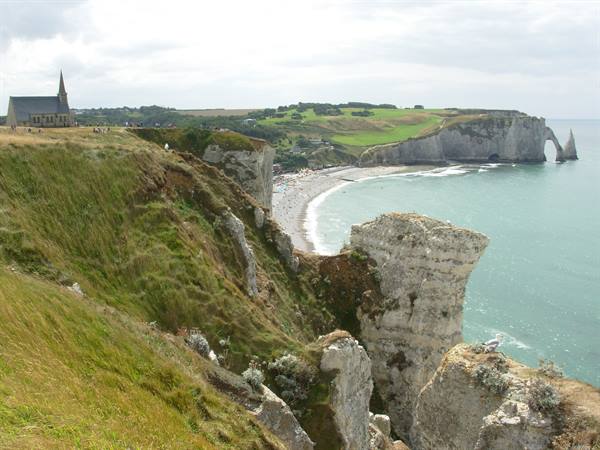 Chapel on chalk cliffs above Étretat beach, overcast sky