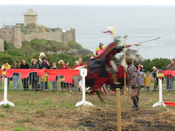 Knight jousting at a medieval reenactment beneath Fort-la-Latte castle walls