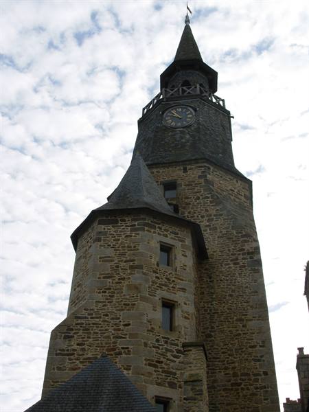 Stone clock tower with pointed spire against a cloudy sky