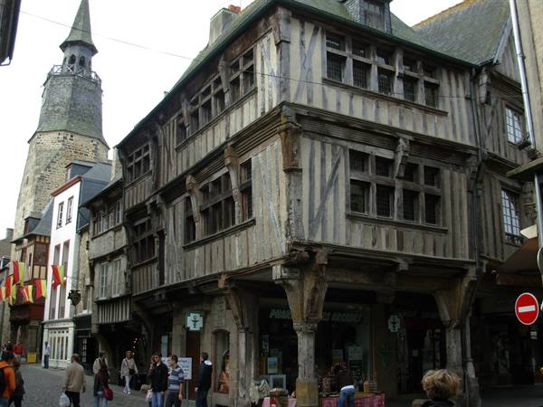Half-timbered wooden houses on the square, stone bell tower and pedestrians