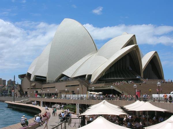 Tourists under umbrellas near the white sails of Sydney Opera House