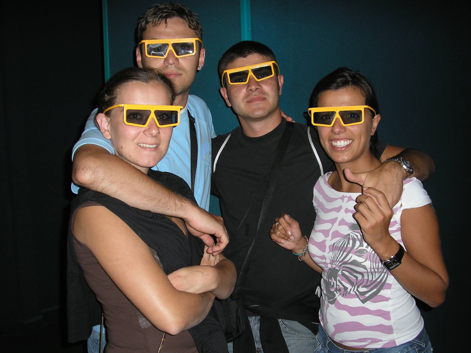 Four friends wearing yellow 3D glasses smiling at the cinema museum