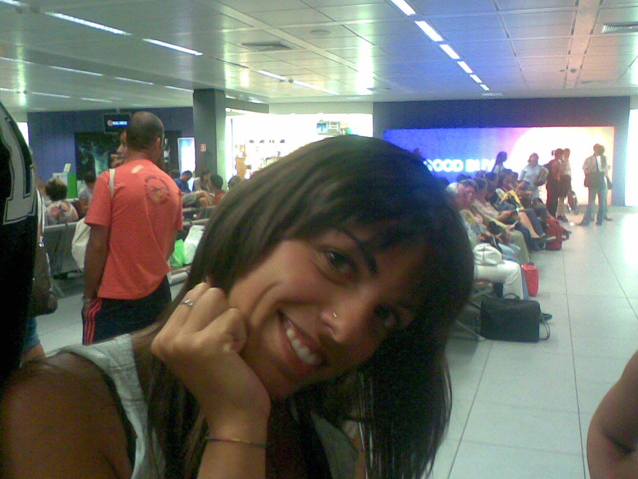 Smiling woman in an airport waiting hall, travelers seated nearby
