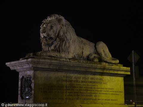Stone lion statue illuminated at night on the Chain Bridge