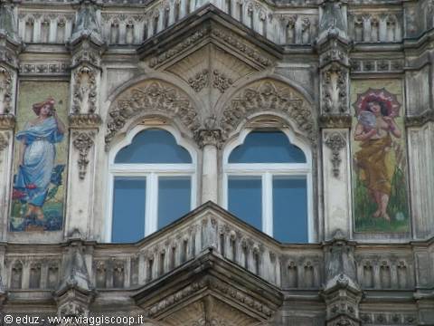 Neo-Gothic stone facade with arched windows and painted female figures