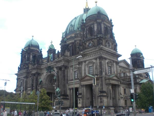 Berlin Cathedral stone facade with green domes, people and traffic lights below