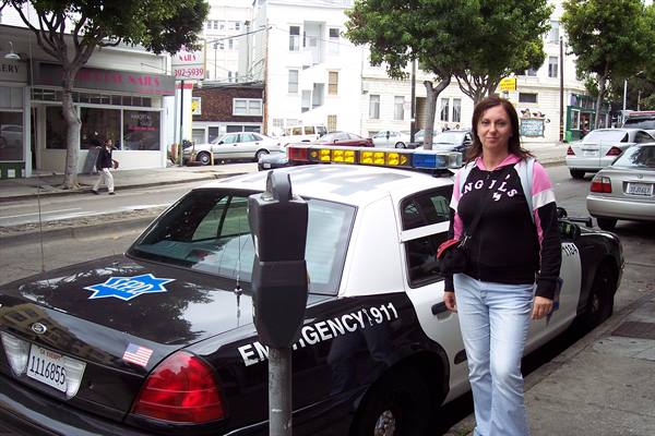 Woman posing next to a San Francisco police car on the street