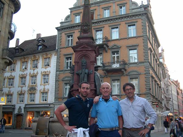 Three men pose in front of the Herkules fountain in Herrengasse, Graz