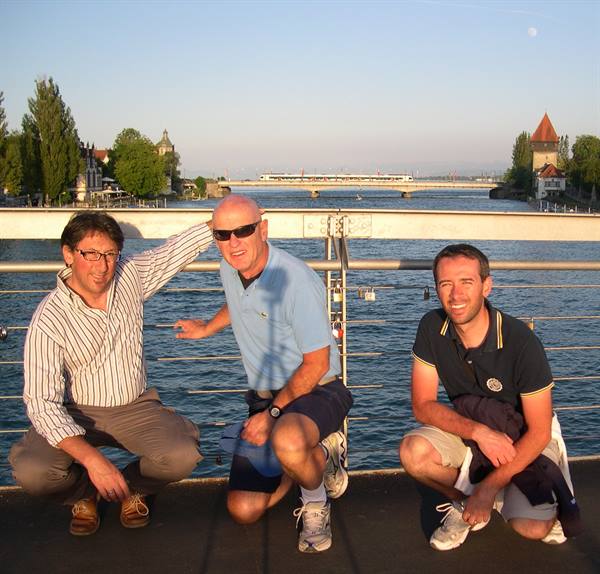 Three friends crouching on the Rhine bridge in Konstanz, golden evening light