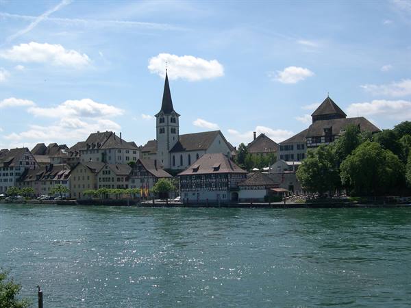 White church spire by the Rhine river in Stein am Rhein, historic houses in sunlight
