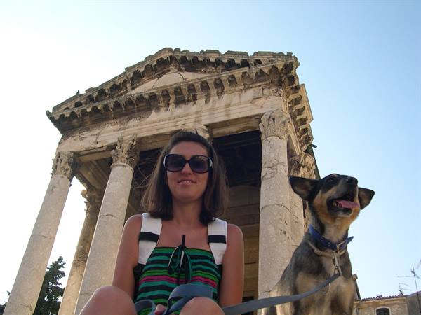 Woman with sunglasses and dog in front of the Temple of Augustus, Pula