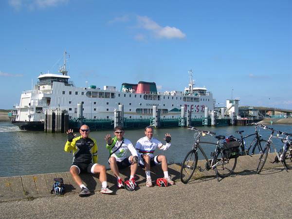 Three cyclists sitting on the quay in front of TESO ferry with bikes