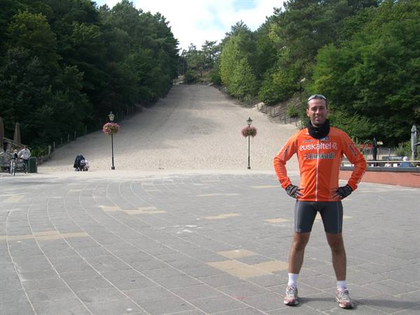 Cyclist in orange jersey posing on the square before the sandy slope