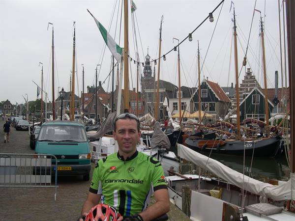 Cyclist in green Cannondale jersey at Hoorn harbor among traditional wooden sailing ships
