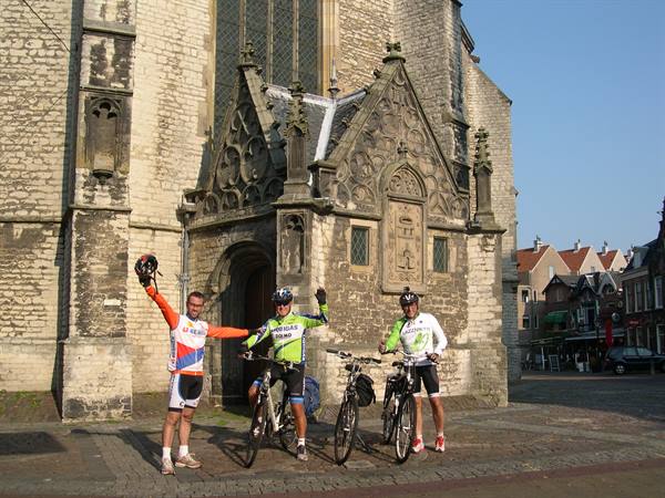 Three cyclists with bikes in front of Gouda's gothic church