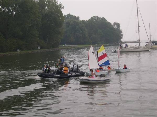 Inflatables and small sailboats with children on the lake under grey sky
