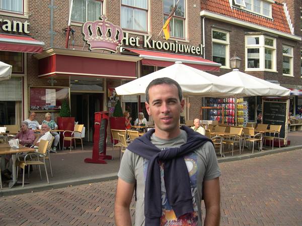 Man in front of the Het Kroonjuweel café with outdoor tables and umbrellas