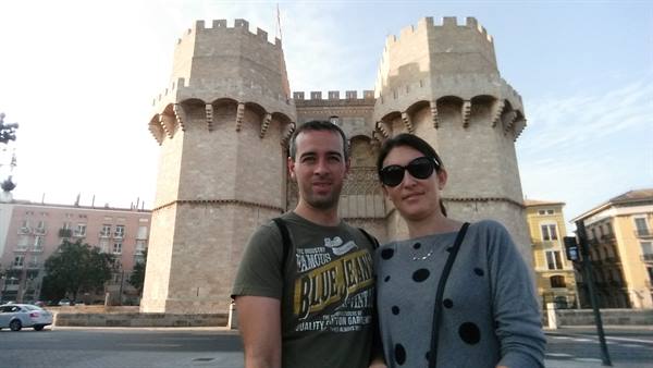 Couple in front of Valencia's Torres de Serranos, light stone, morning light