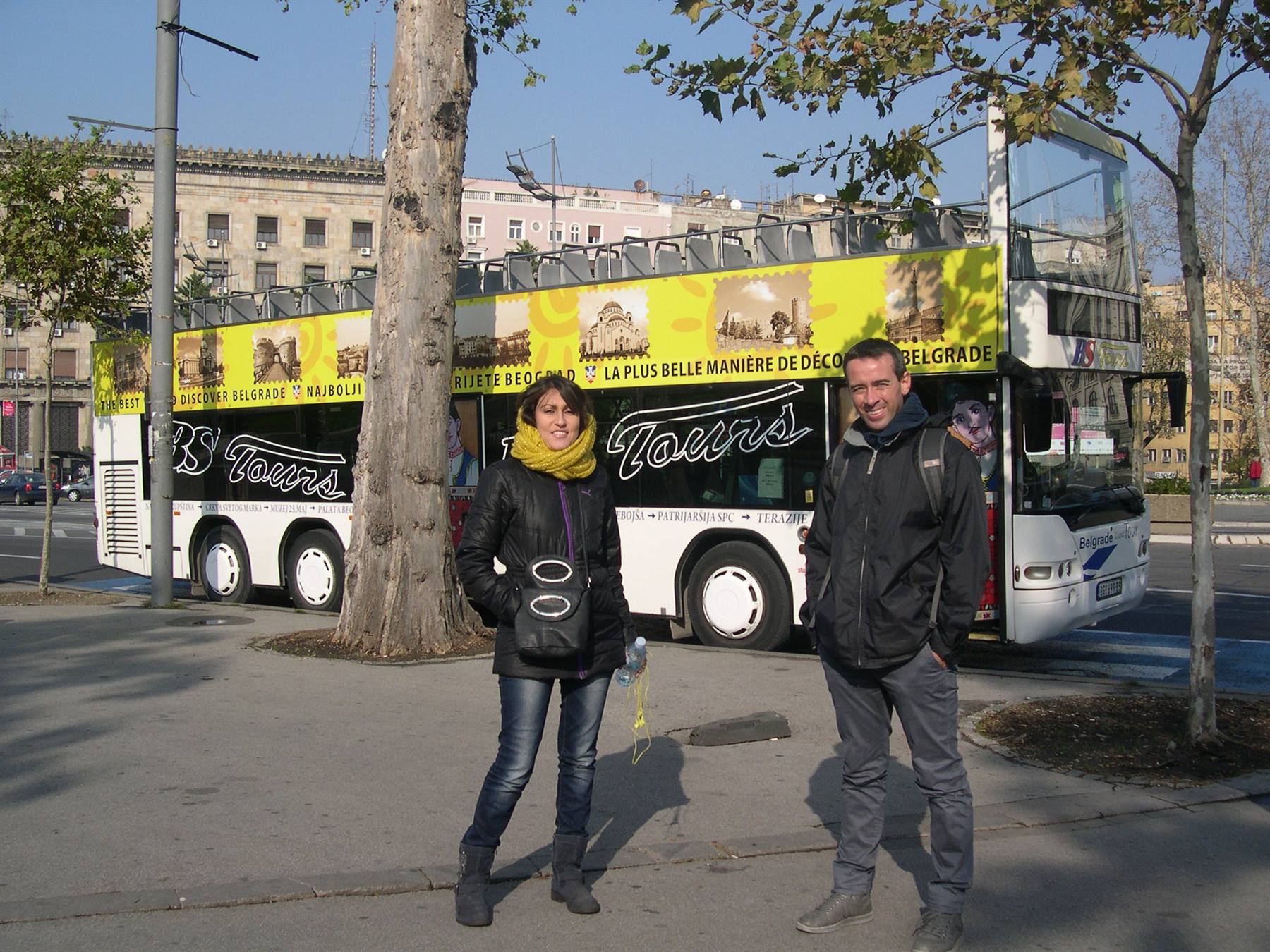 Coppia davanti al bus turistico scoperto BS Tours a Belgrado