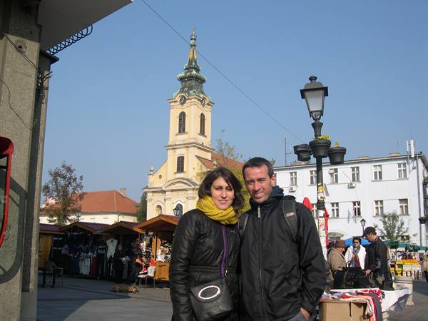smiling couple in a square in front of a yellow church market