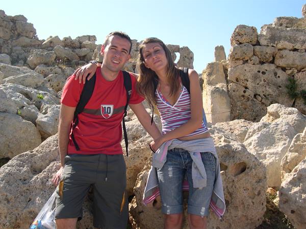 Two smiling tourists pose among the limestone megalithic walls of Ħaġar Qim temple