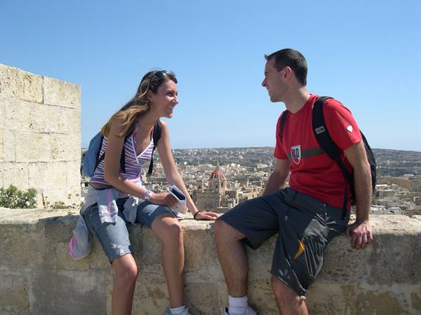 Two hikers sitting on a stone wall above Victoria citadel, Gozo