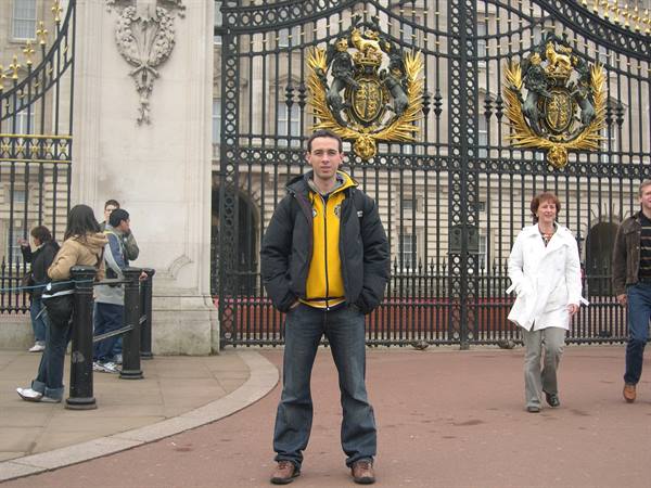 Tourist posing in front of the gilded gates of Buckingham Palace, London