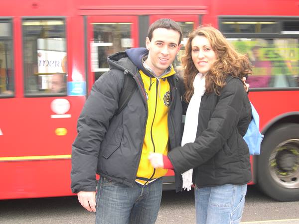 Smiling couple in front of a red city bus on the street