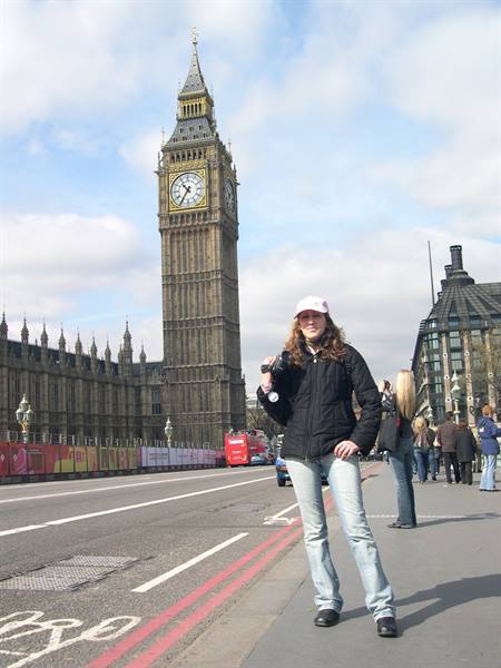 Tourist with camera posing beside Big Ben and Westminster under cloudy sky