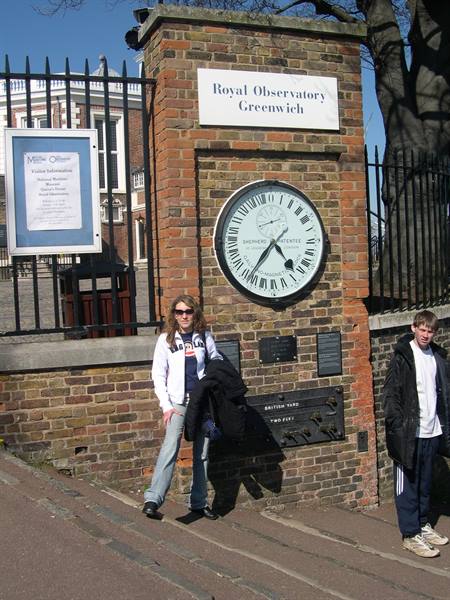 Two people beside the 24-hour Shepherd gate clock at the Royal Observatory, Greenwich