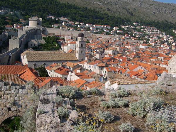 Red rooftops and bell tower of Dubrovnik from the walls, green hill behind