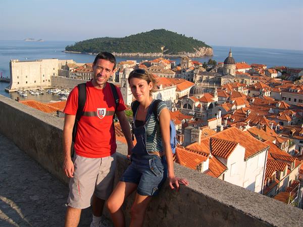 Two tourists on Dubrovnik city walls among red roofs and the sea
