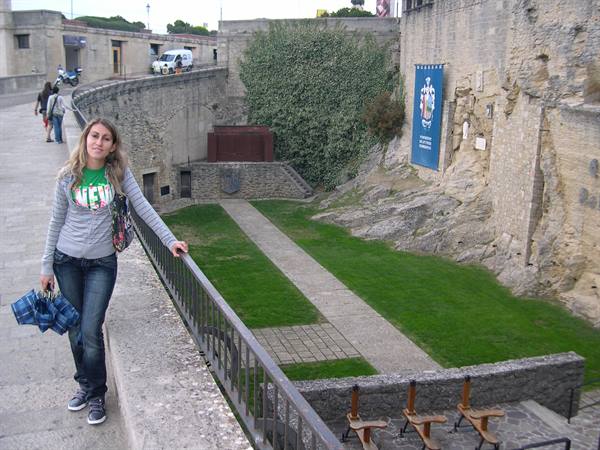 Blonde woman leaning on railing above the Avignon fortress walls