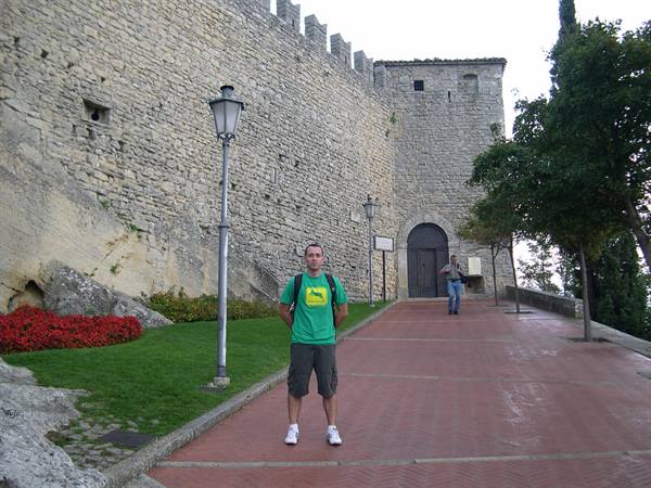 Tourist in green shirt beneath the medieval walls of San Marino
