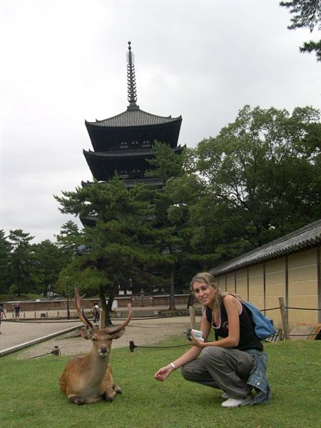 Woman crouching beside a seated deer, Kofuku-ji pagoda in Nara