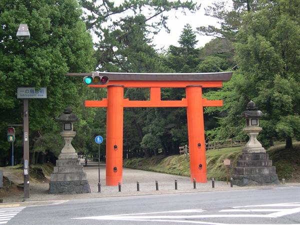 Large red torii gate at shrine entrance, with traffic lights and lanterns