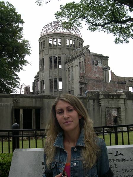 Tourist in front of Hiroshima's Genbaku Dome, concrete and brick ruins, gray sky