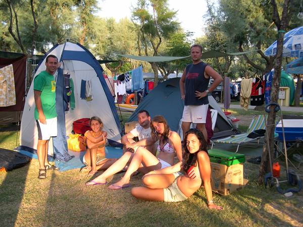 Friends relaxing at a campsite among tents and parasols in the afternoon