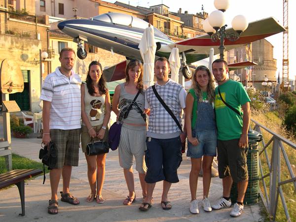 Six friends posing in front of a training aircraft displayed on the promenade
