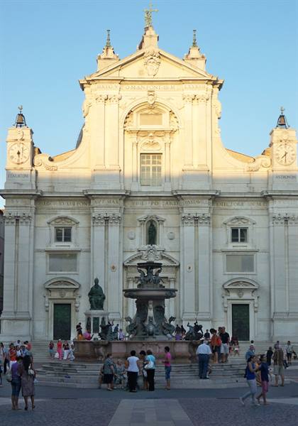 Sunlit white facade of Loreto Basilica, fountain and tourists in front