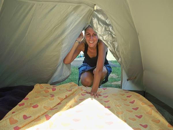 Smiling girl peeking through the tent opening with heart-patterned blanket