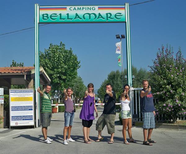 Six friends pose thumbs up under the Camping Bellamare entrance sign