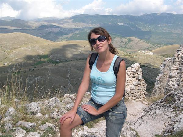 Girl with backpack and sunglasses by dry-stone walls in the mountains